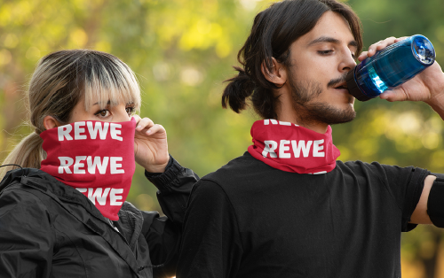 Mann und Frau tragen bedruckten Schlauchschal von multiloop mit Rewe Logo